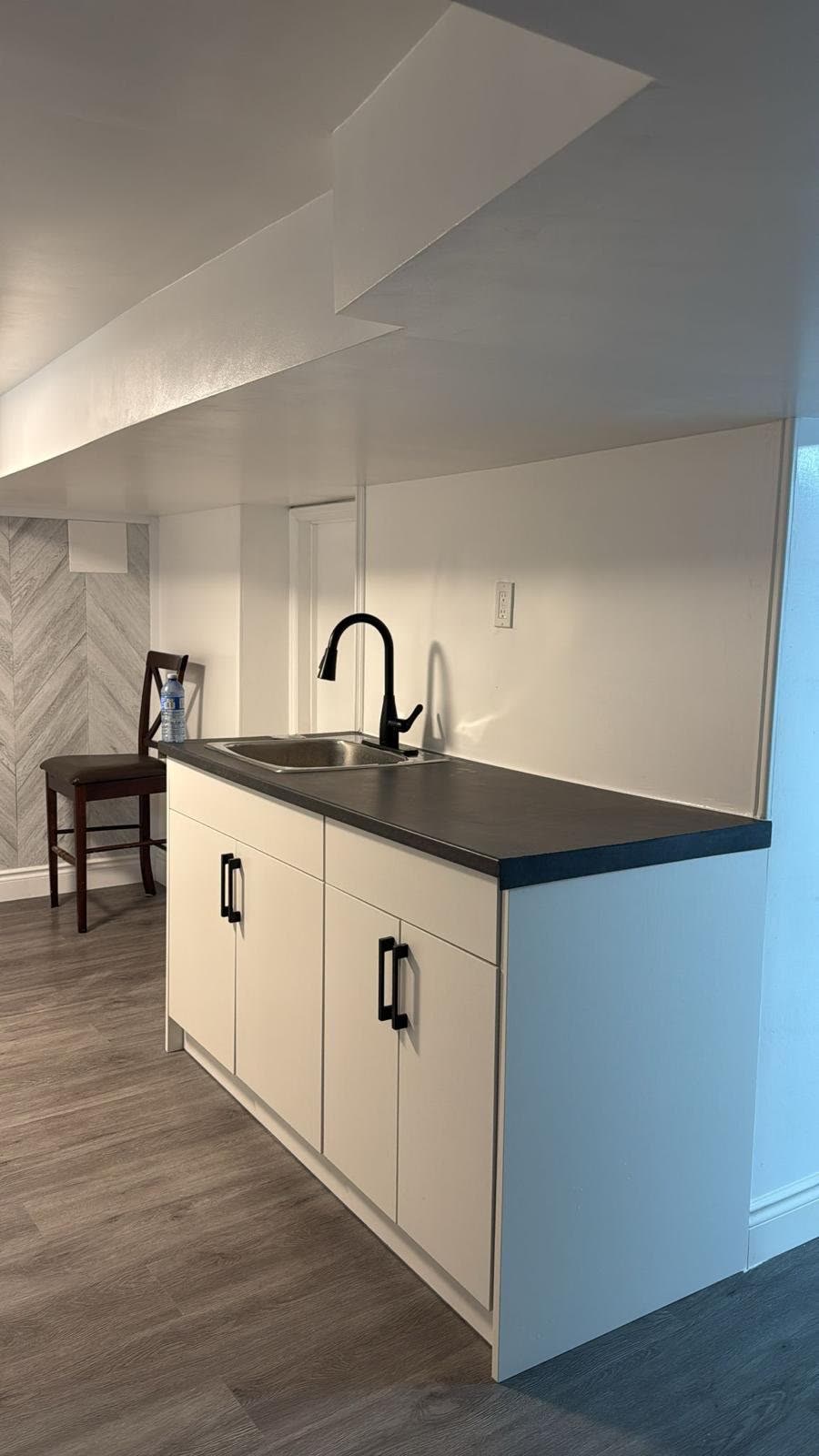 Basement kitchenette with white cabinets and black countertop, Barrie renovation