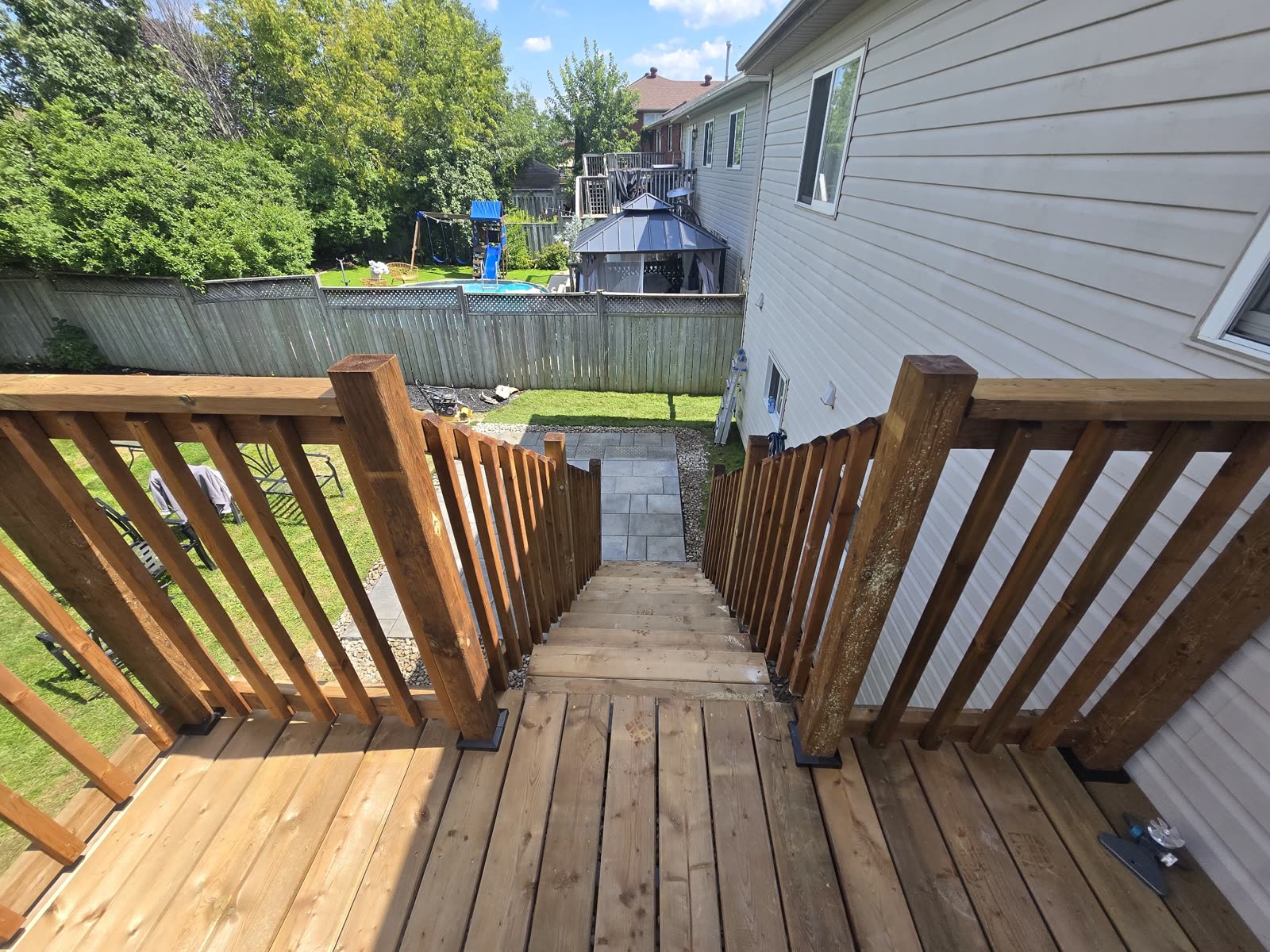 View from wooden deck down to interlocking patio, backyard renovation Barrie