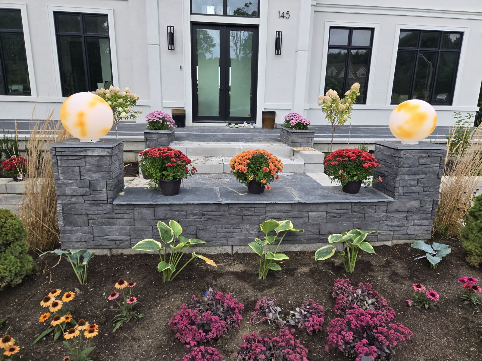 Landscaped front entrance with stone wall and flowers