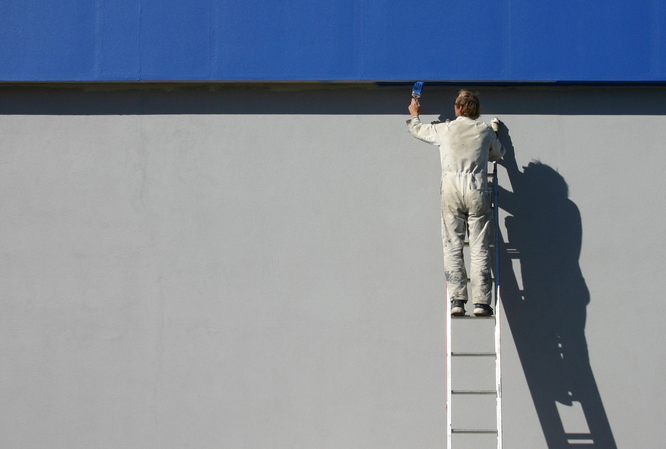 Professional painter cutting in paint on a building exterior