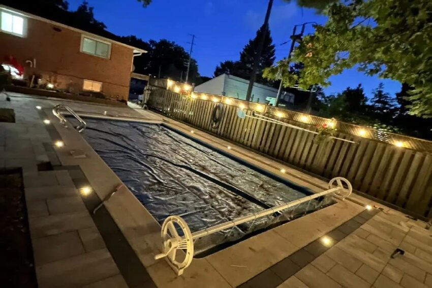 Backyard pool at night with interlocking patio and landscape lighting, Barrie